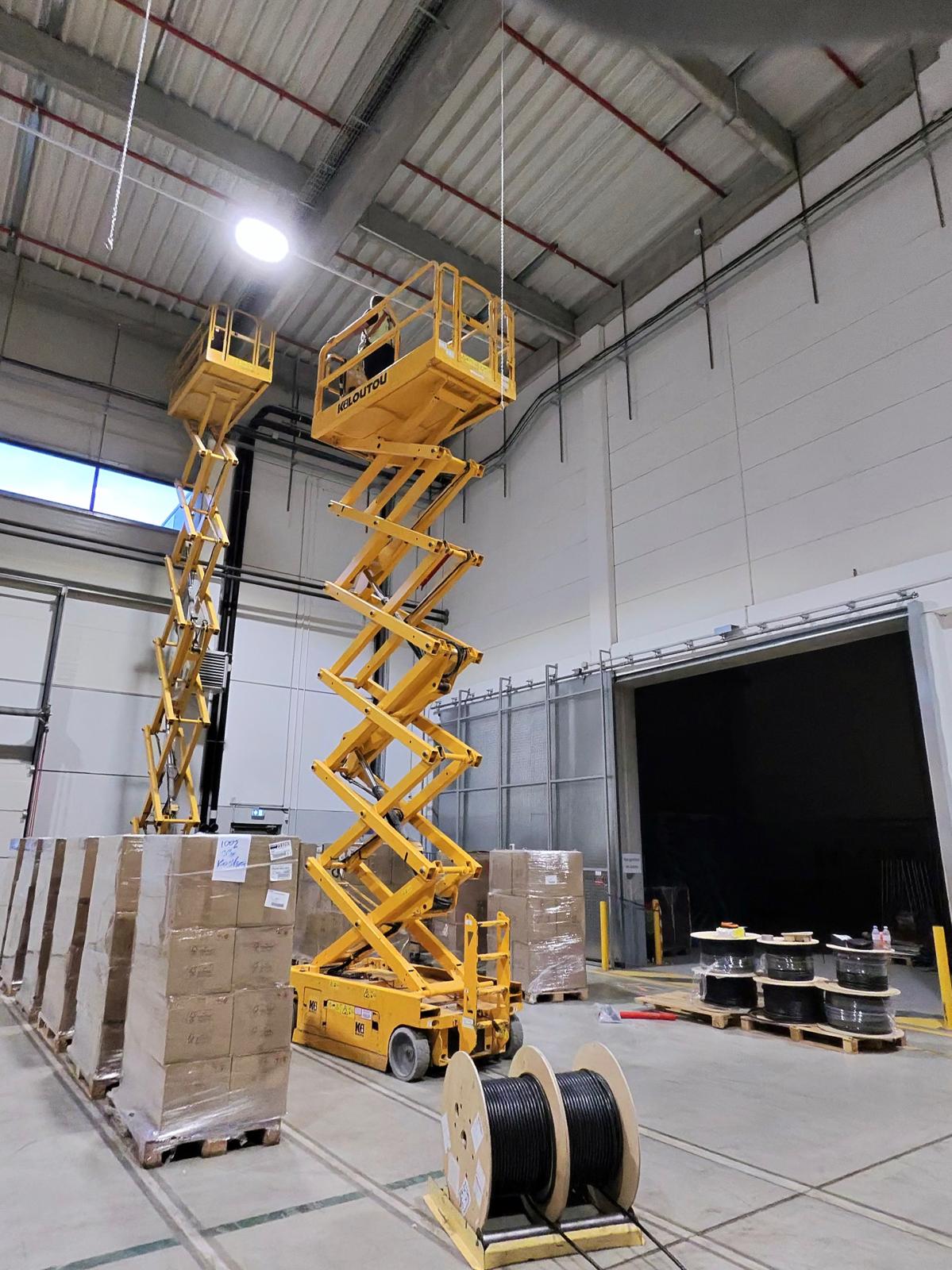 Deux nacelles déployées et tourets de câbles en bâtiment industriel